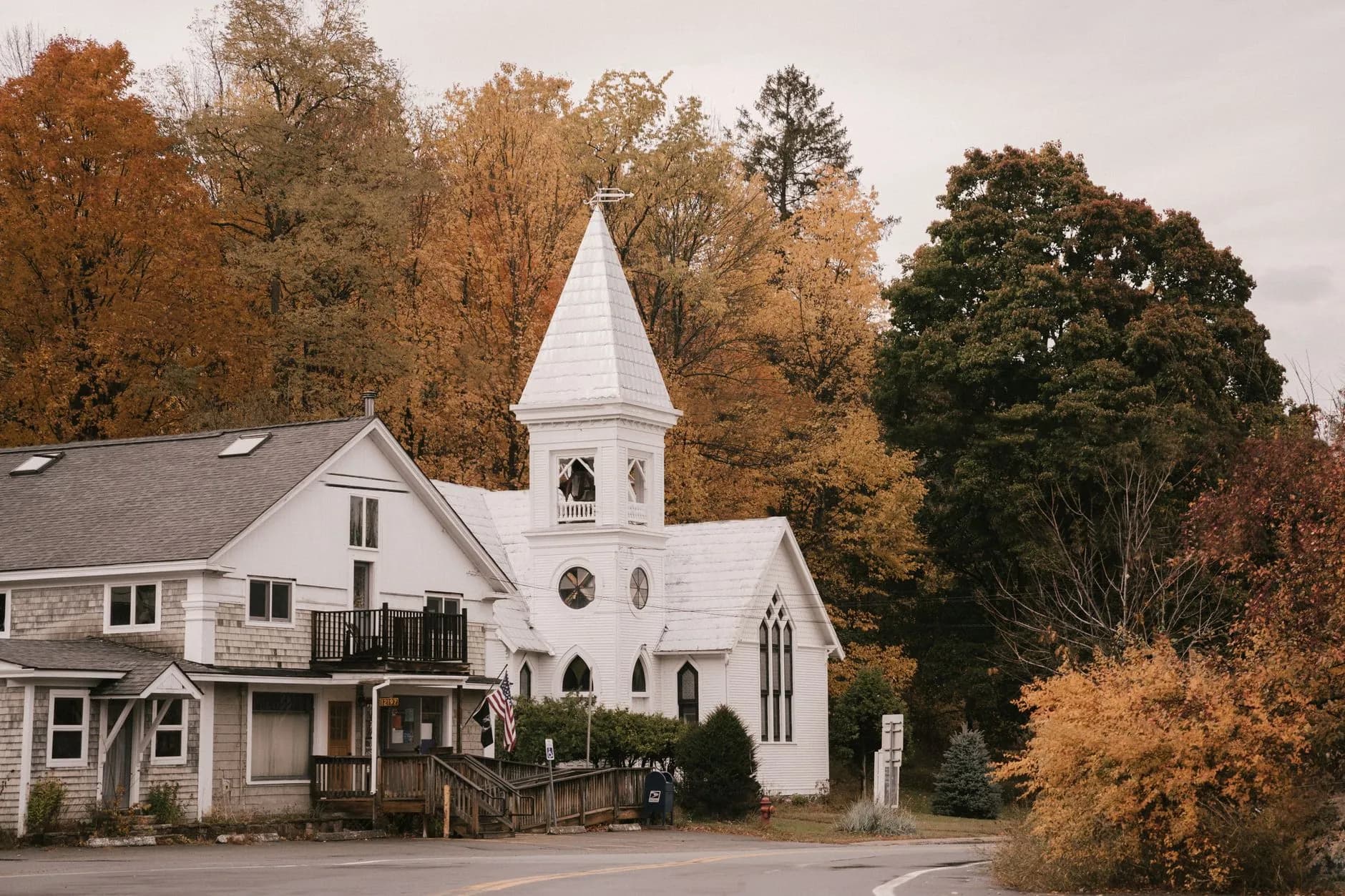 A white church and houses among autumn trees in a New England town