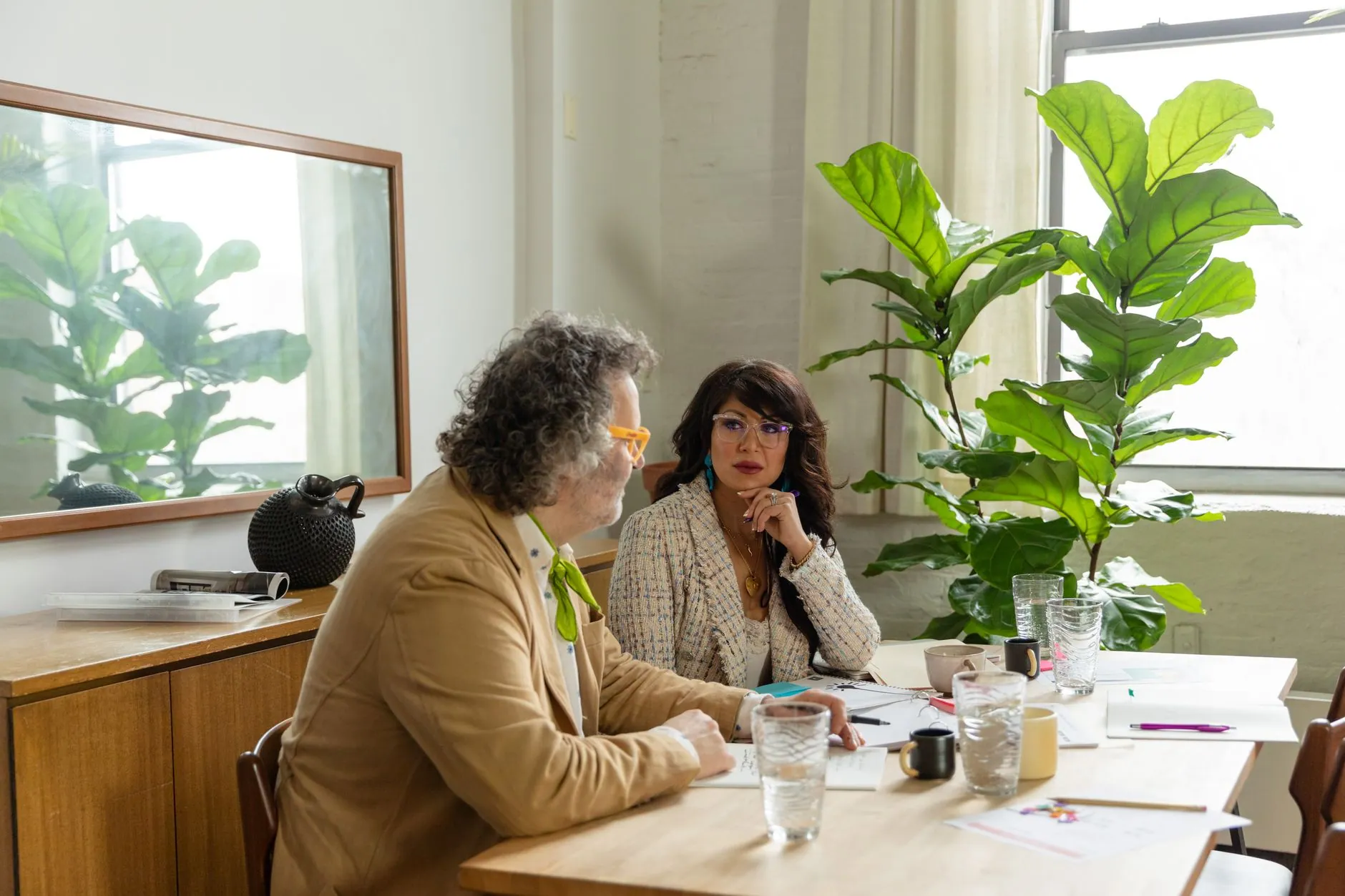 Two people talking at a table in a sunny office