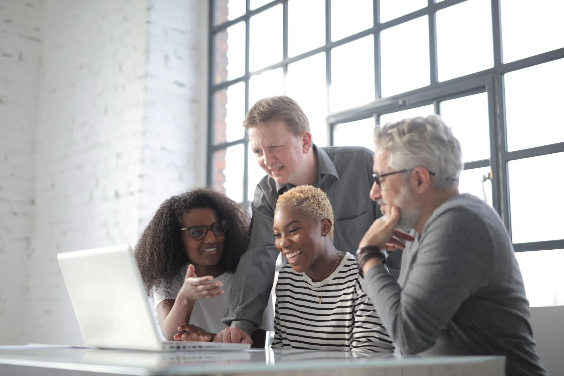 Colleagues smiling together around a laptop