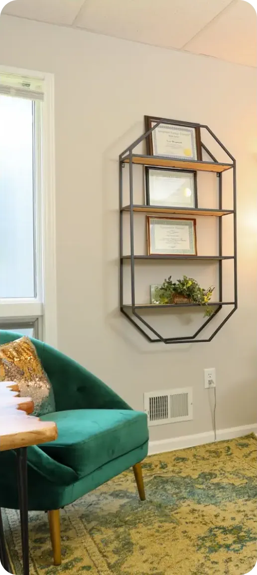 An Inner Clarity therapy room with a green velvet chair and wood shelves