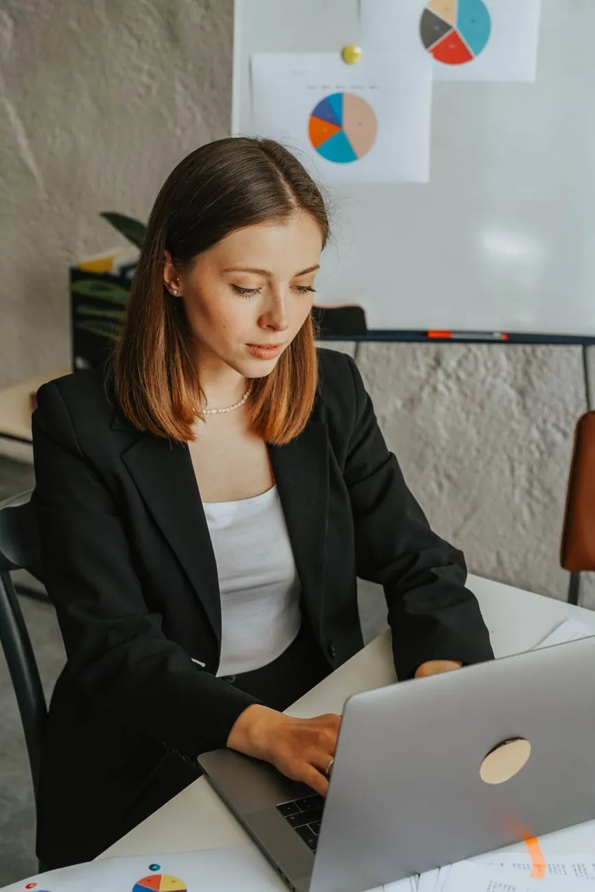 A woman working on a laptop in an office