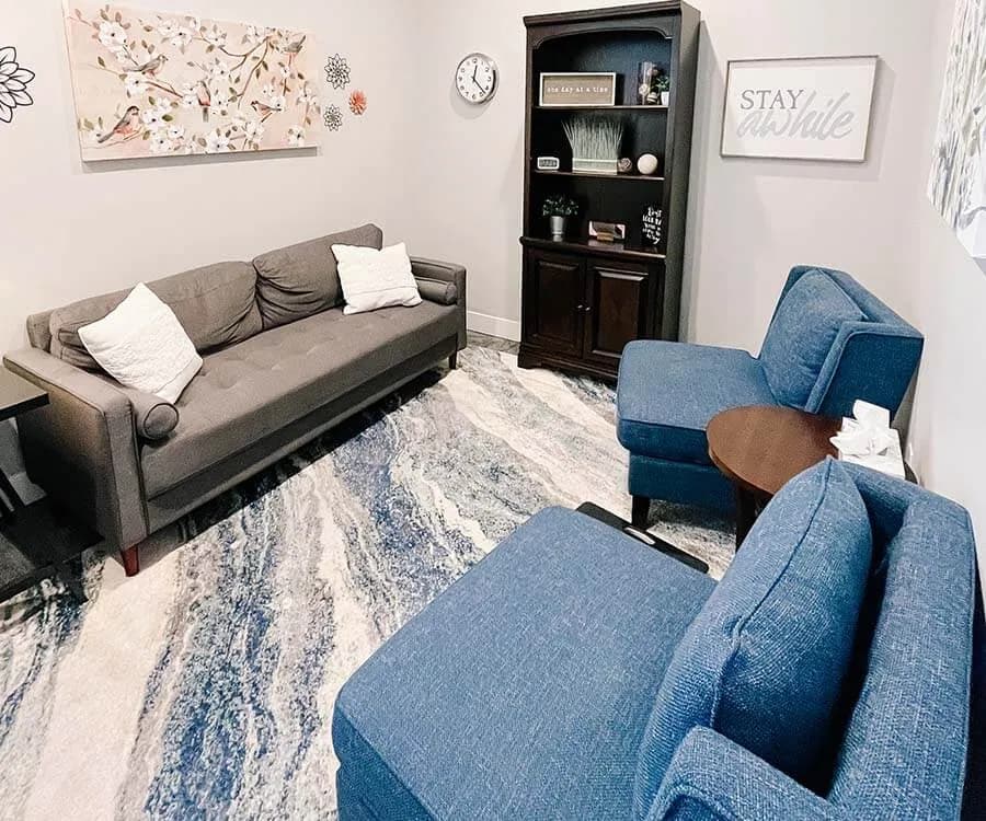 A Mountain View Family Therapy room with a gray sofa and blue armchairs