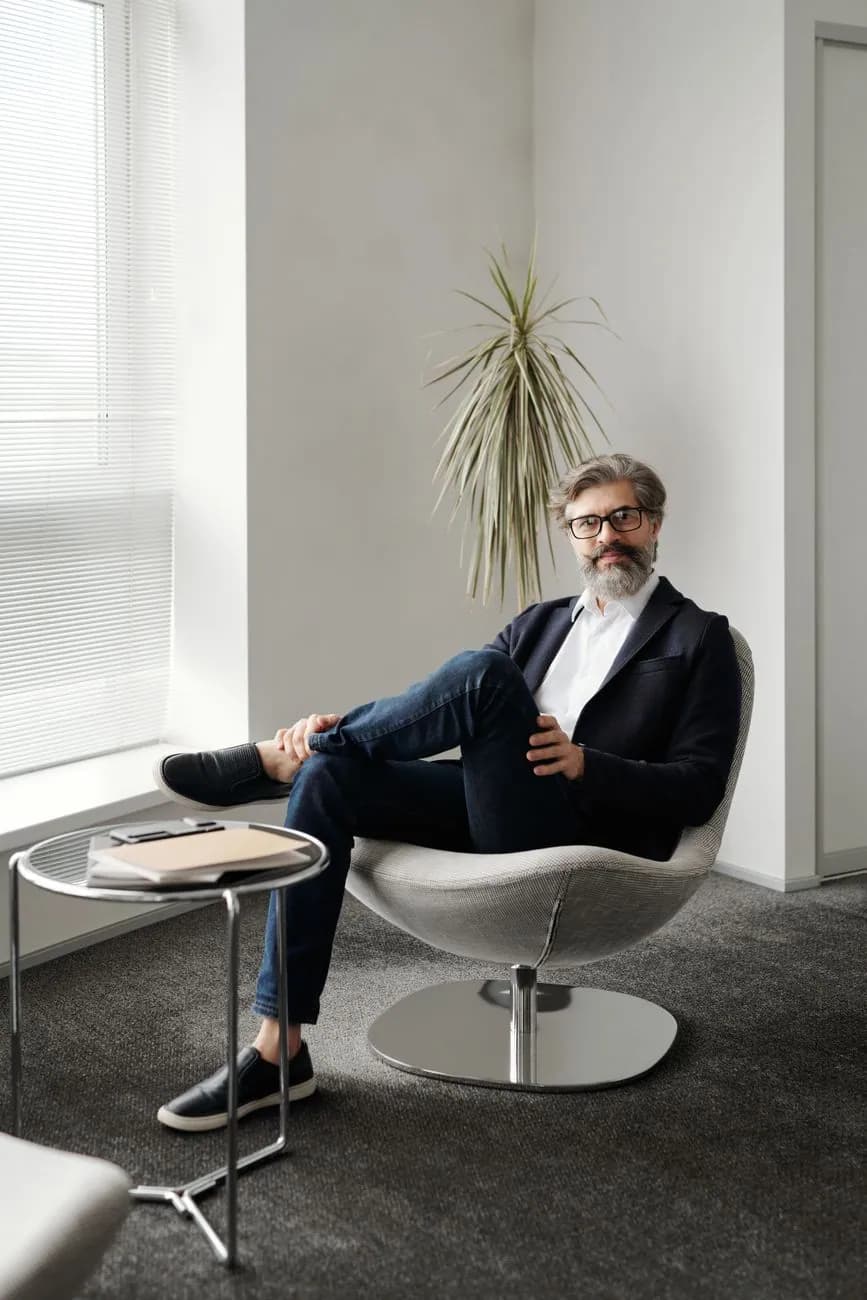 A man seated in an armchair in a bright office