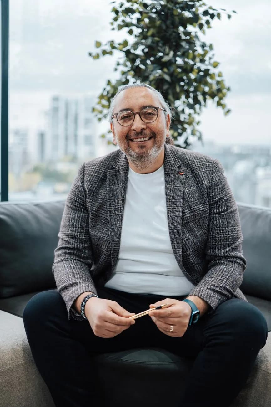 A smiling man seated on a sofa in a bright office
