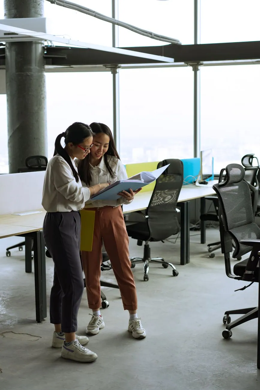 Two colleagues reviewing a folder together in an open office