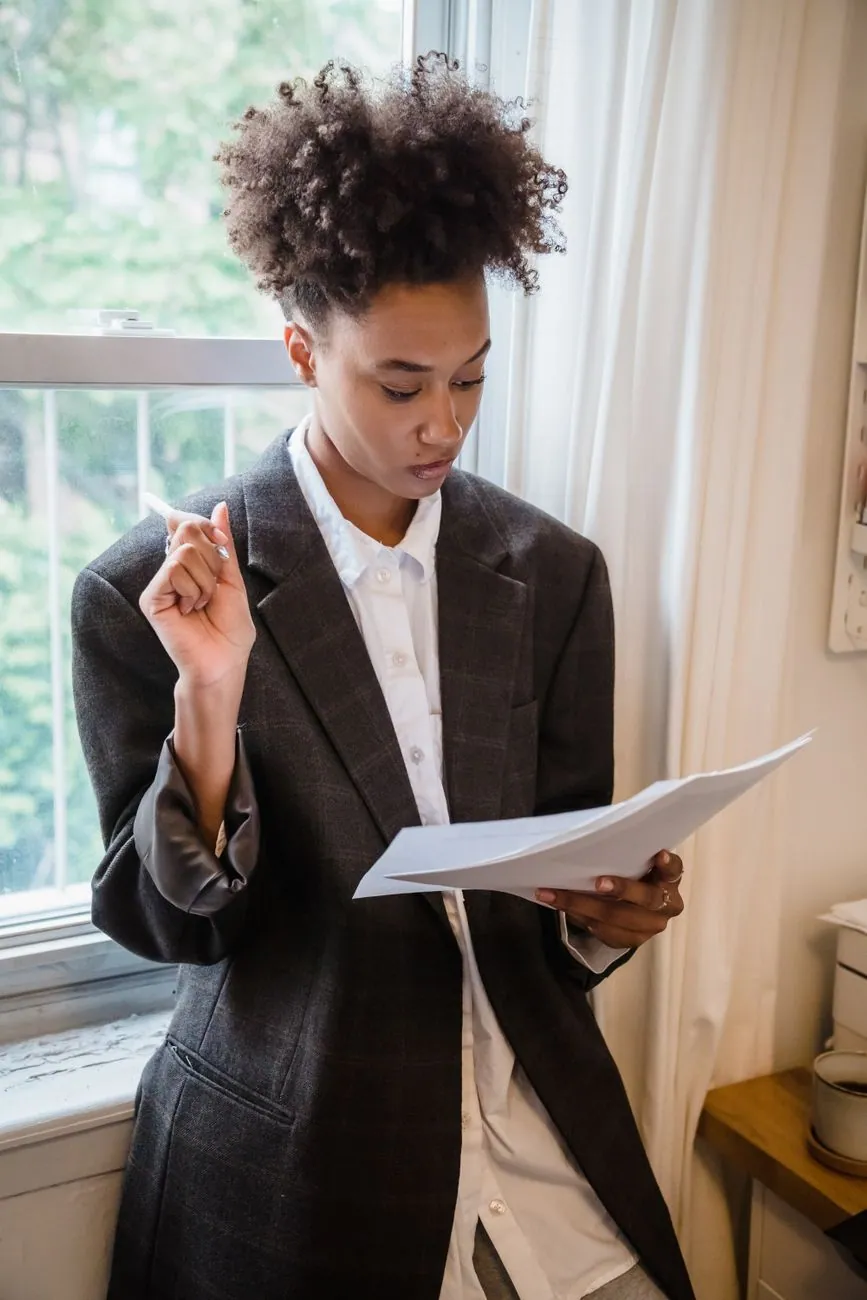 A woman reading through notes by a window
