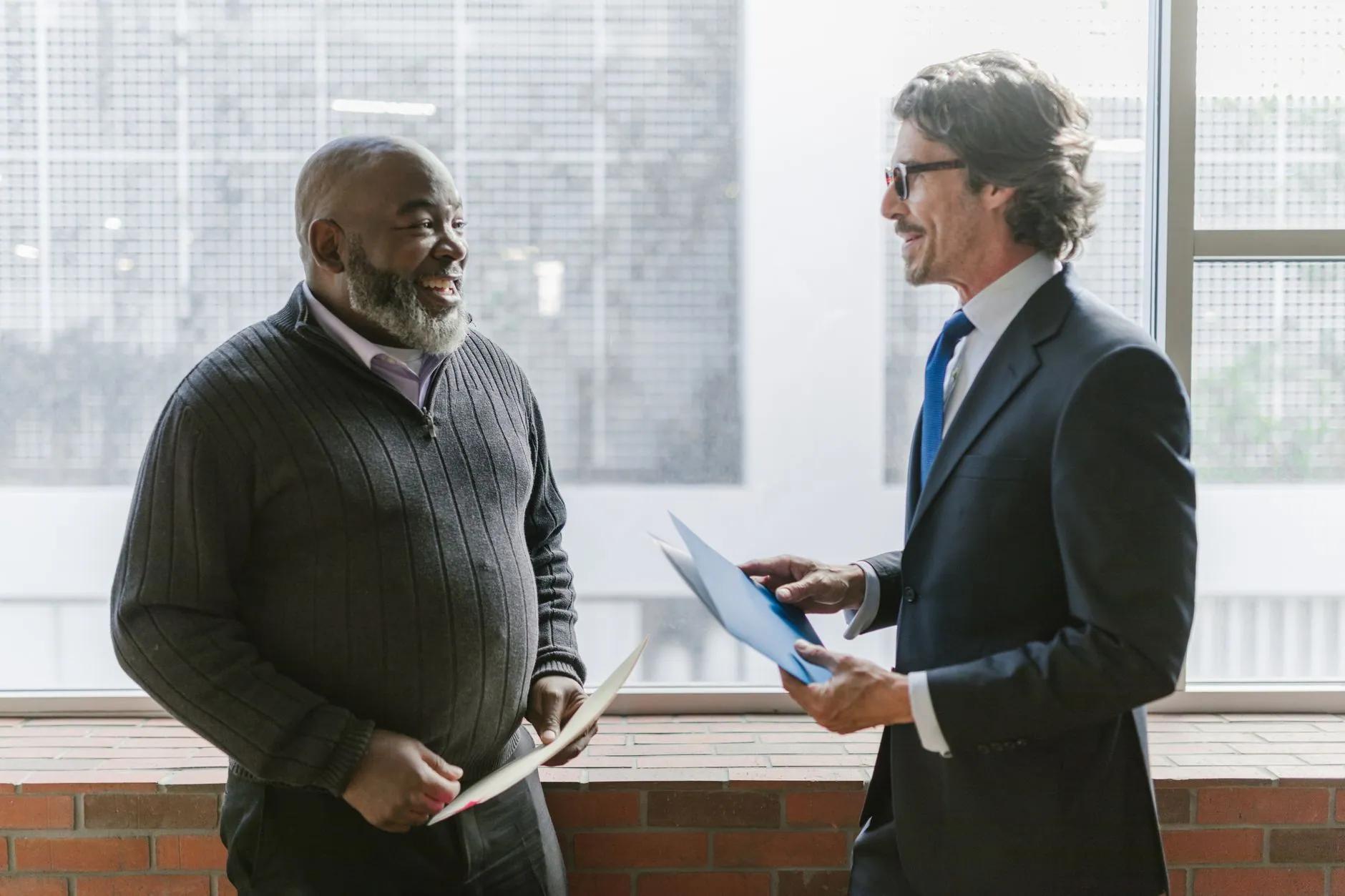 Two colleagues talking through a document by a window
