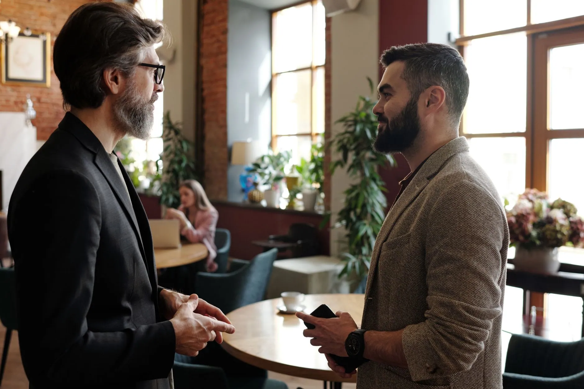 Two men talking in a warm, plant-filled office